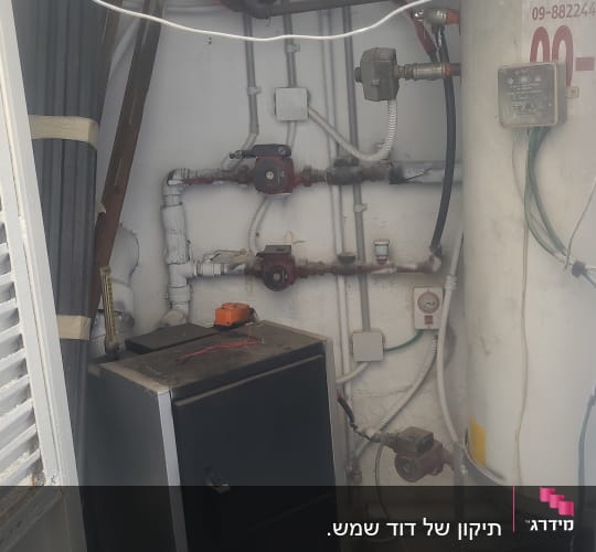 דוד שמש עם צינורות ומד לחץ בחדר שירות